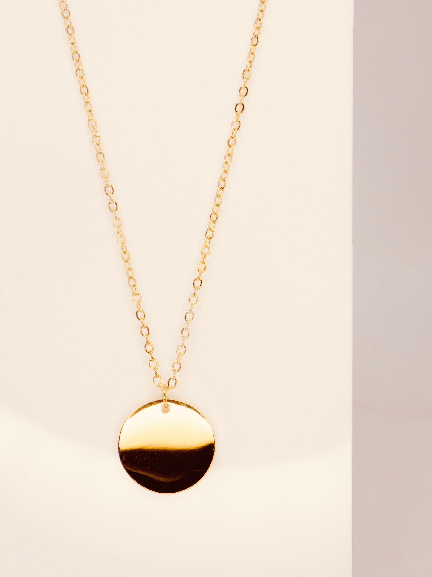 Close-up of tarnish-proof 14K gold plated round disc pendant, showcasing minimalist design for timeless style.