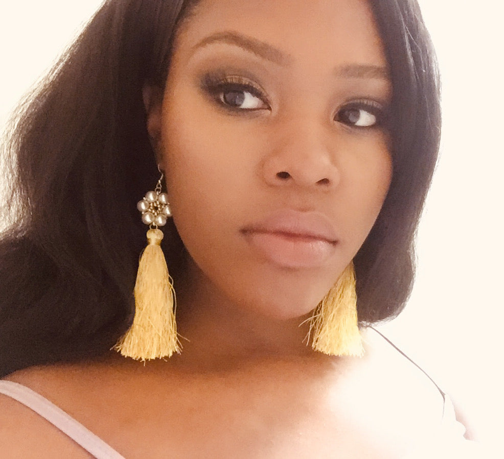 A woman wearing elegant yellow tassel earrings with pearl accents, stylish jewelry design.